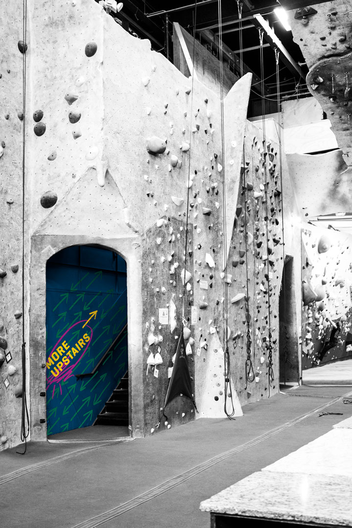 an image of the Stone Gardens gym interior, with a branded mural indicating that there is more climbing available upstairs.